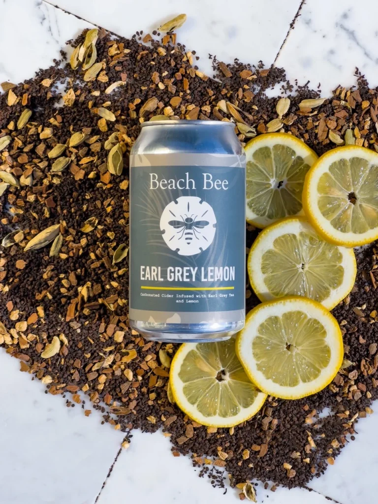 Beach Bee Earl Grey Lemon hard cider with fresh lemon slices and loose Earl Grey tea, highlighting a semi-dry 5% ABV cider made with real ingredients, no added sugar, and no artificial flavors.