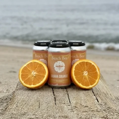 Beach Bee Guava Orange Hard Cider with guava, orange, and pineapple displayed on the beach in Long Branch, New Jersey.